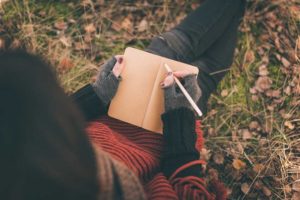 girl journaling outside under at tree in the fall
