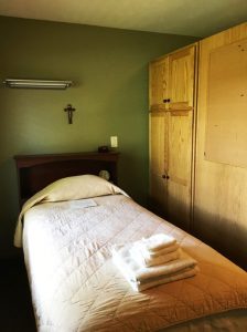 single bed with cross hanging above headboard - St. Gregory Recovery Center - faith based drug and alcohol treatment center