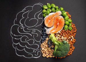 chalkboard with brain drawn on it and healthy foods laying on half of it - brain health