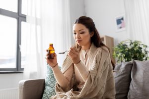 pretty Asian woman taking cold or cough syrup at home - codeine cold