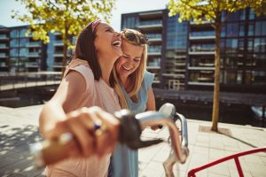 Anxiety and Loneliness in Recovery, two female friends laughing and smiling while walking outdoors - anxiety and loneliness